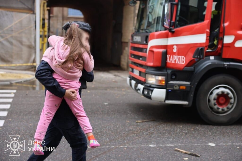 Firefighter carrying a child from burning kindergarten in Kharkiv